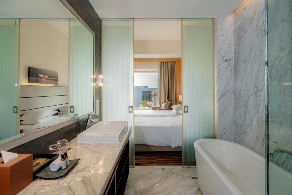 a bathroom with a tub and a sink and a mirror at Hyatt Regency Pune Hotel & Residences in Pune a bathroom with a tub and a sink and a mirror at Hyatt Regency Pune Hotel & Residences in Pune