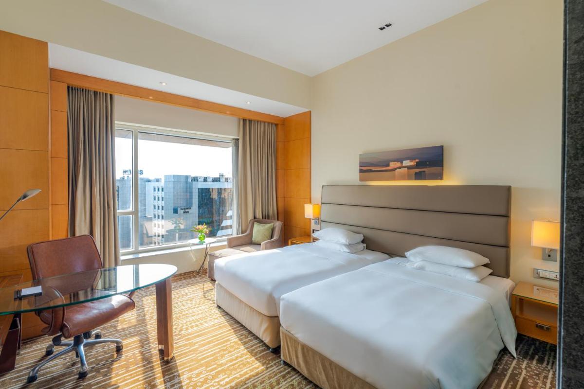a hotel room with two beds and a table at Hyatt Regency Pune Hotel & Residences in Pune
