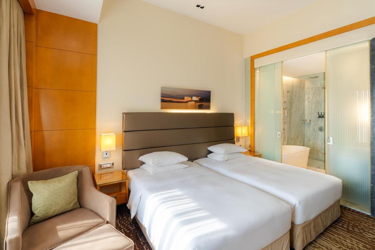 a bedroom with a large white bed and a chair at Hyatt Regency Pune Hotel & Residences in Pune