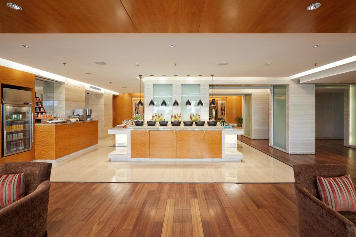 a lobby of a hotel with wooden floors and a kitchen at Hyatt Regency Pune Hotel & Residences in Pune