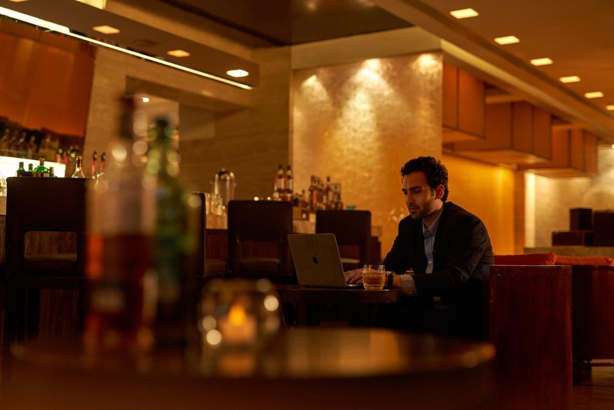 a man sitting at a table with a laptop in a restaurant at Hyatt Regency Pune Hotel & Residences in Pune