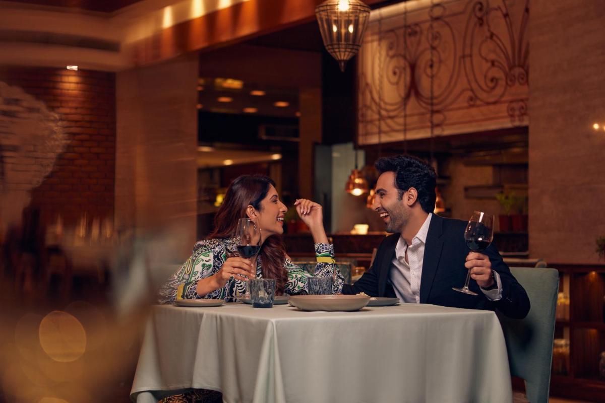 a man and woman sitting at a table with wine glasses at Hyatt Regency Pune Hotel & Residences in Pune