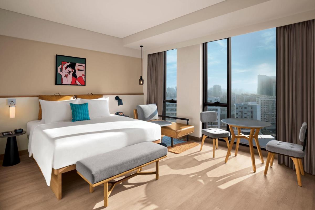 a bedroom with a bed and a room with a view at Moxy Mumbai Andheri West in Mumbai a bedroom with a bed and a room with a view at Moxy Mumbai Andheri West in Mumbai