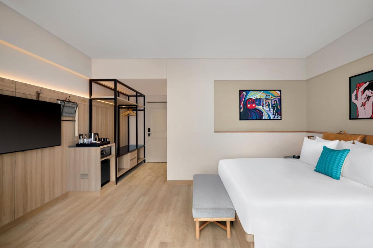 a bedroom with a large white bed and a tv at Moxy Mumbai Andheri West in Mumbai