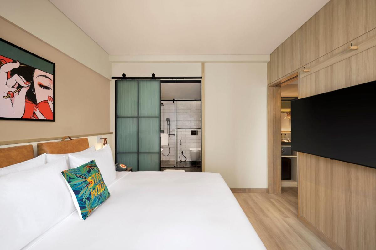 a bedroom with a white bed and a flat screen tv at Moxy Mumbai Andheri West in Mumbai
