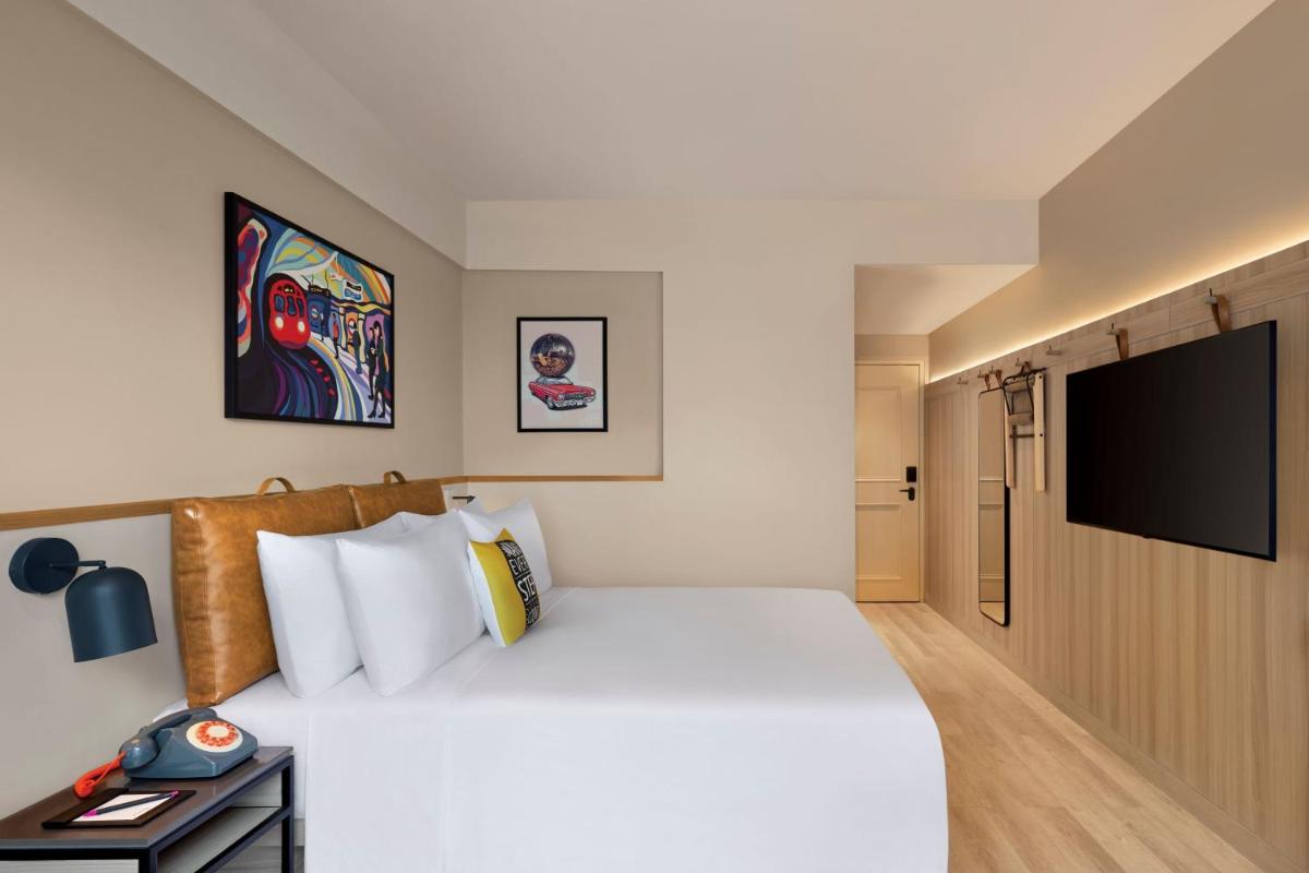 a bedroom with a large bed and a flat screen tv at Moxy Mumbai Andheri West in Mumbai