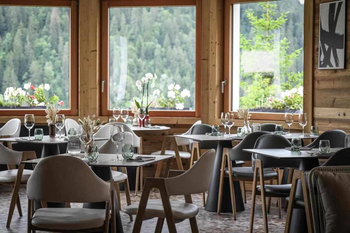 une salle à manger avec tables, chaises et fenêtres dans l'établissement Fleur De Neige Châtel, à Châtel