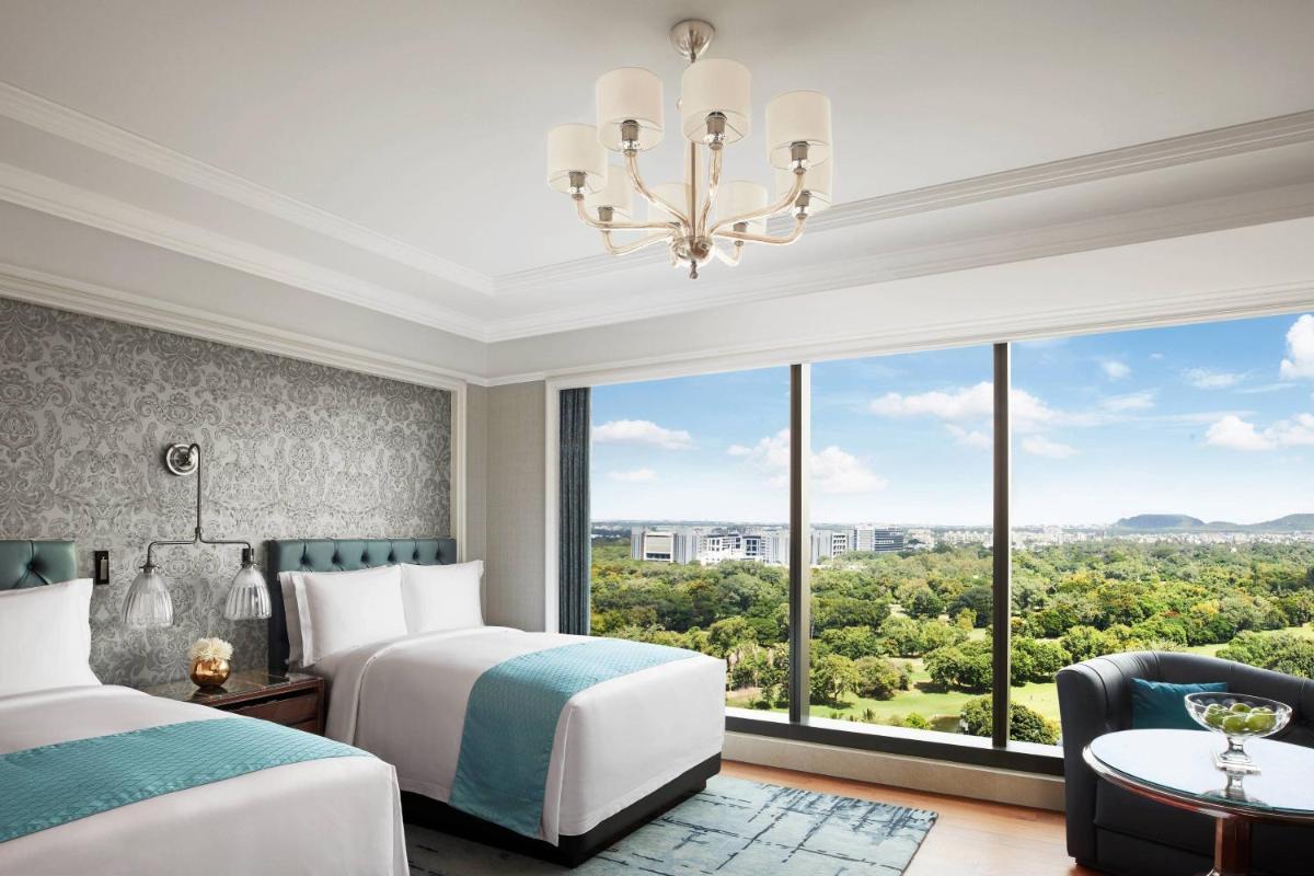 a bedroom with two beds and a large window at The Ritz-Carlton, Pune in Pune