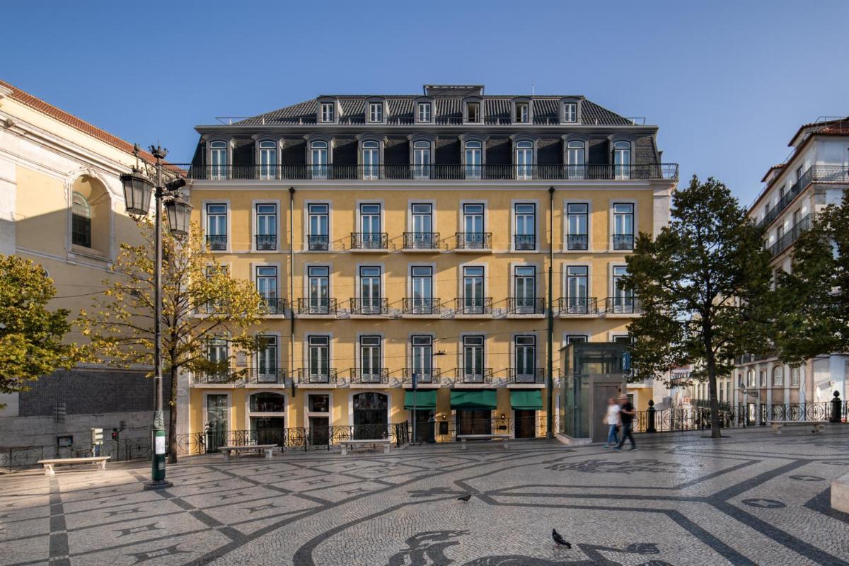 um grande edifício amarelo numa rua da cidade em Bairro Alto Hotel em Lisboa