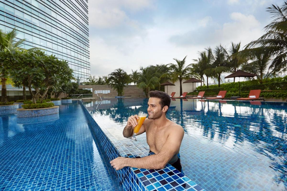 a man in a swimming pool drinking a banana at The Westin Mumbai Garden City in Mumbai