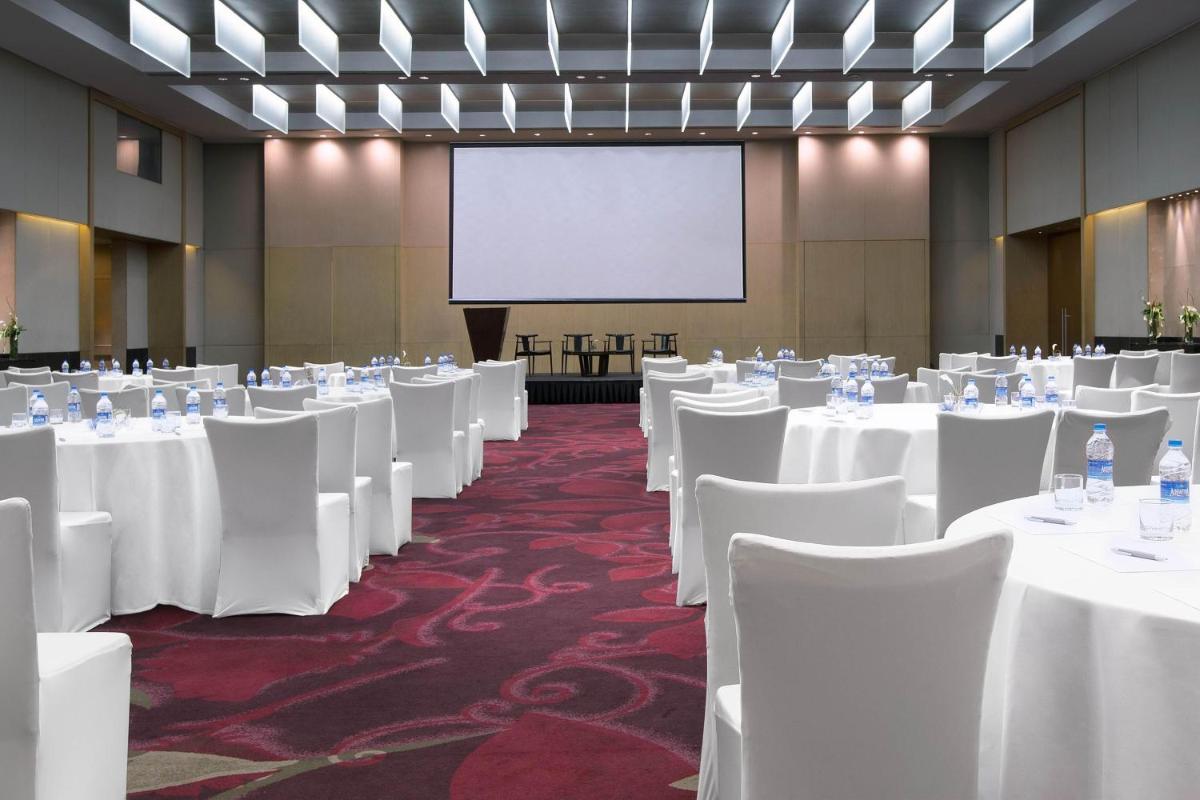 a conference room with white tables and chairs and a screen at The Westin Mumbai Garden City in Mumbai
