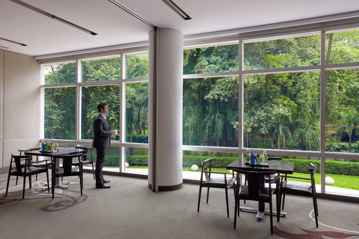 a man standing in a room with tables and windows at The Westin Mumbai Garden City in Mumbai