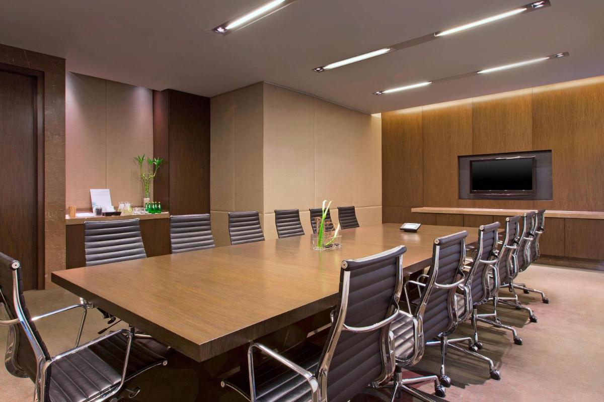 a conference room with a large wooden table and chairs at The Westin Mumbai Garden City in Mumbai