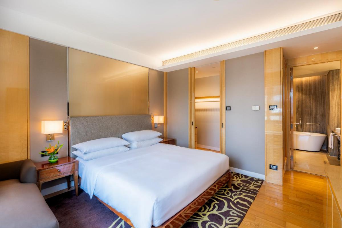 a bedroom with a large white bed and a bathroom at Hyatt Regency Pune Hotel & Residences in Pune
