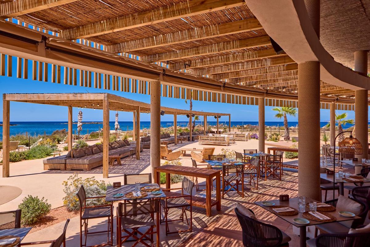 un restaurante en la playa con mesas y sillas en Universal Grand León & Spa, en Colonia de Sant Jordi