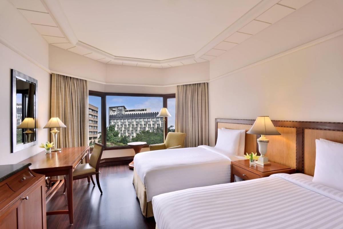 a hotel room with two beds and a desk at Hyderabad Marriott Hotel & Convention Centre in Hyderabad