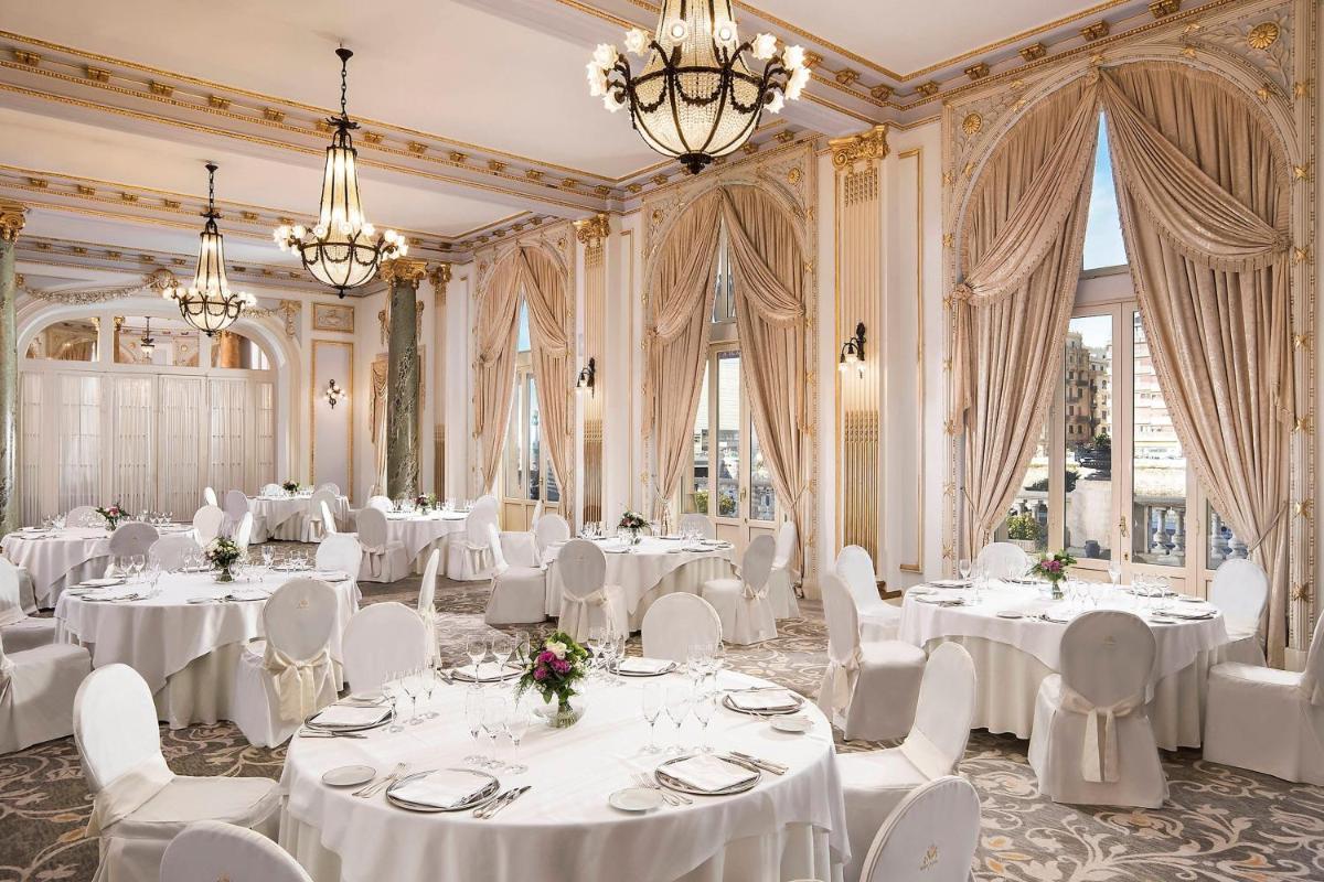 una sala de banquetes con mesas y sillas blancas y lámparas de araña en Hotel Maria Cristina, a Luxury Collection Hotel, San Sebastian, en San Sebastián