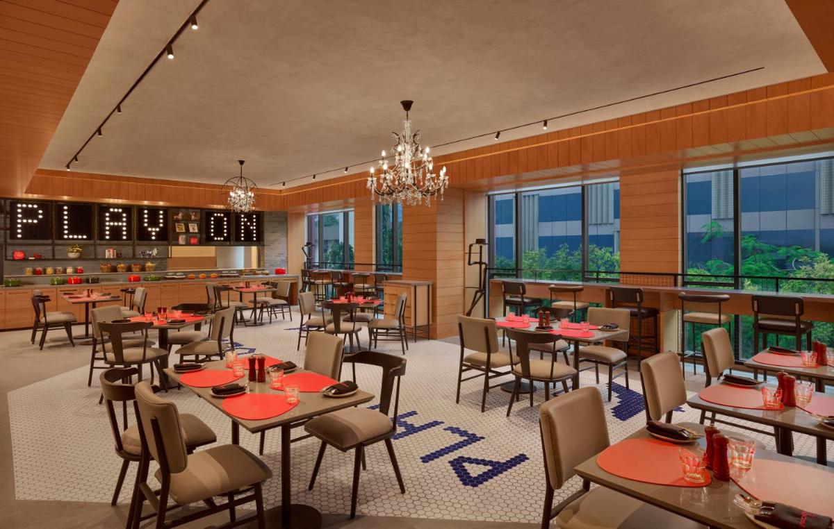 a restaurant with tables and chairs and windows at Moxy Mumbai Andheri West in Mumbai