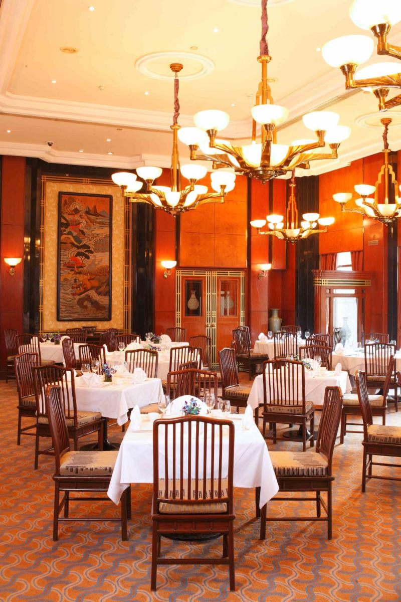 a dining room with white tables and chairs and chandeliers at Eros Hotel New Delhi, Nehru Place in New Delhi a dining room with white tables and chairs and chandeliers at Eros Hotel New Delhi, Nehru Place in New Delhi
