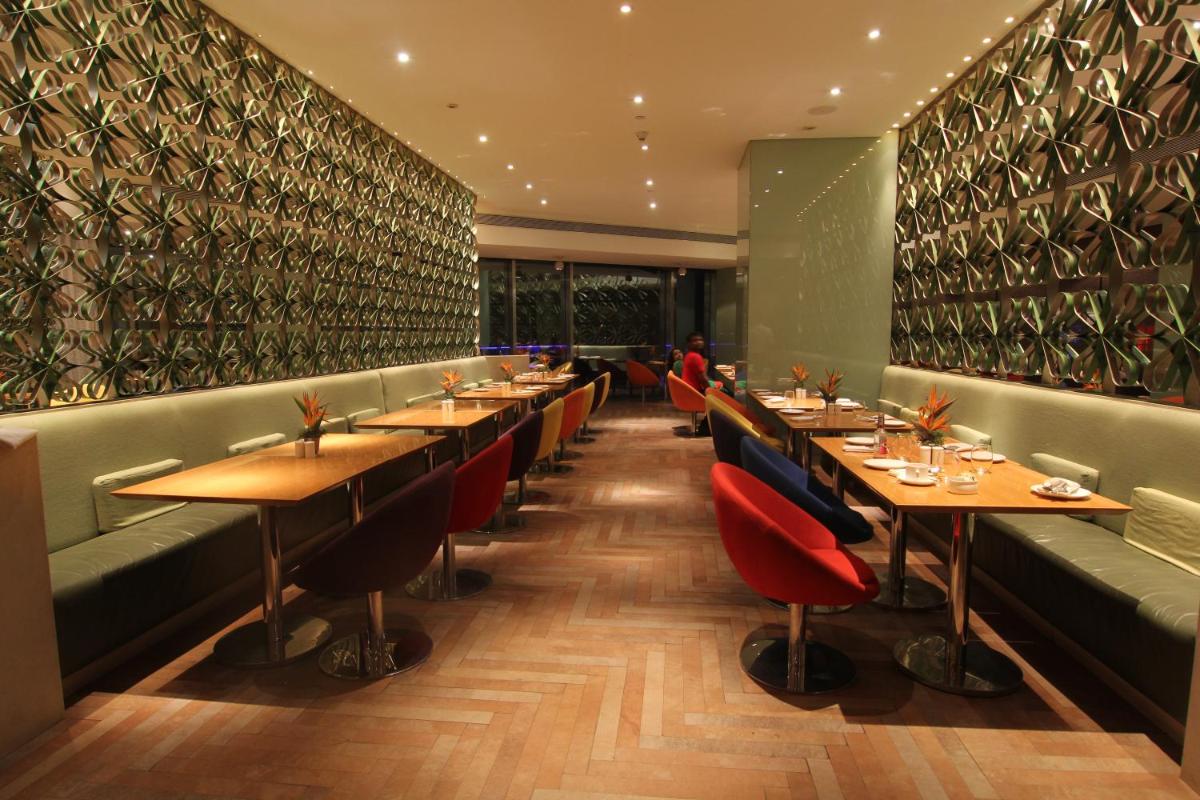 a restaurant with long tables and red chairs at The Park Hyderabad, Banjara Hills near Hussain Sagar Lake in Hyderabad a restaurant with long tables and red chairs at The Park Hyderabad, Banjara Hills near Hussain Sagar Lake in Hyderabad