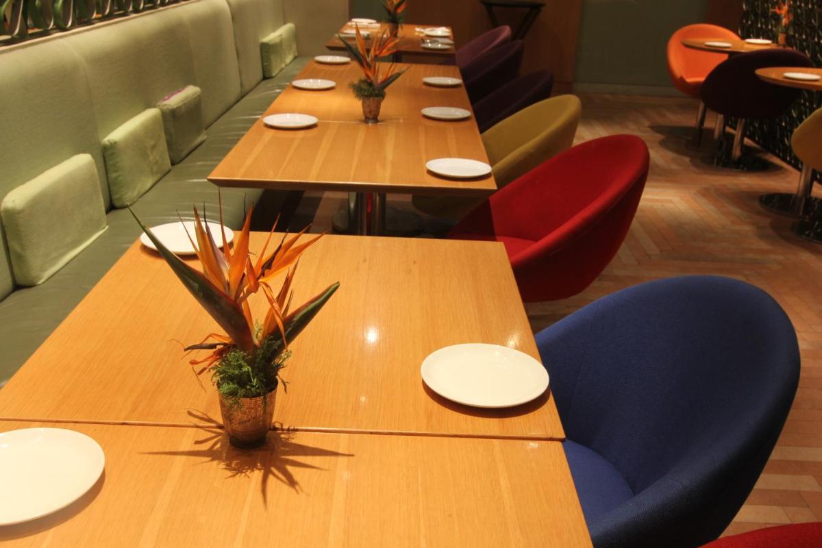 a long table in a restaurant with plates and plants at The Park Hyderabad, Banjara Hills near Hussain Sagar Lake in Hyderabad a long table in a restaurant with plates and plants at The Park Hyderabad, Banjara Hills near Hussain Sagar Lake in Hyderabad
