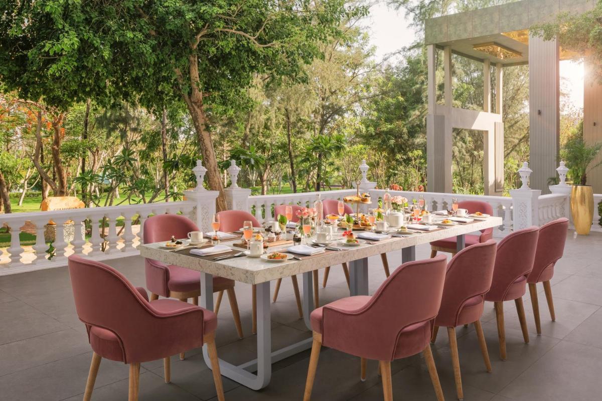 a long table with pink chairs and a white table and chairsearcher at Essentia Luxury Resort & Spa Udaipur in Udaipur