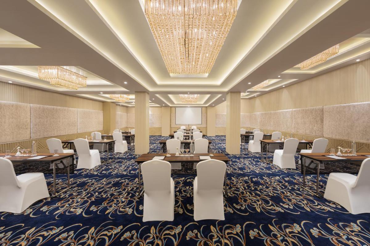 a conference room with tables and chairs and a stage at Essentia Luxury Resort & Spa Udaipur in Udaipur