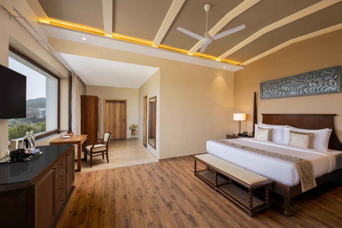 a hotel room with a large bed and a desk at Essentia Luxury Resort & Spa Udaipur in Udaipur