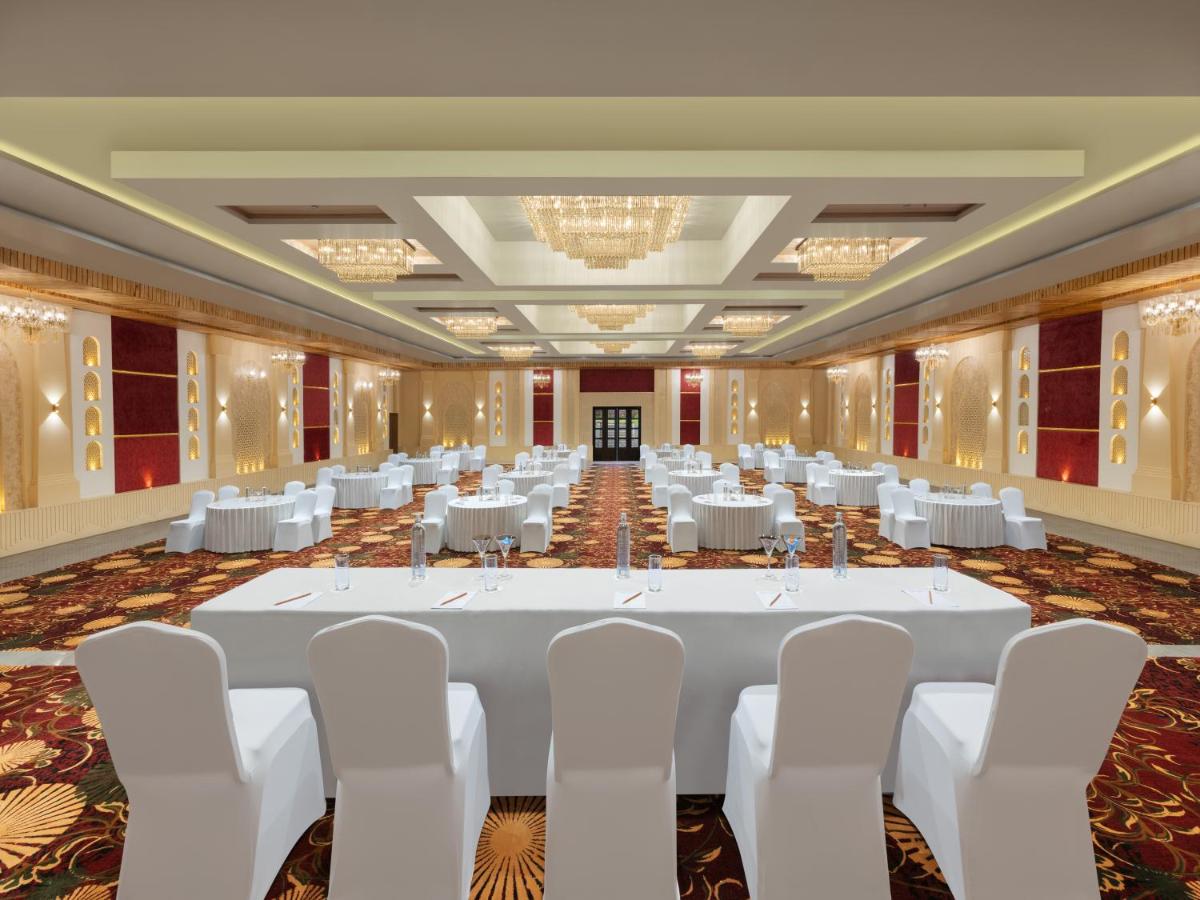 a large banquet hall with white tables and white chairs at Essentia Luxury Resort & Spa Udaipur in Udaipur