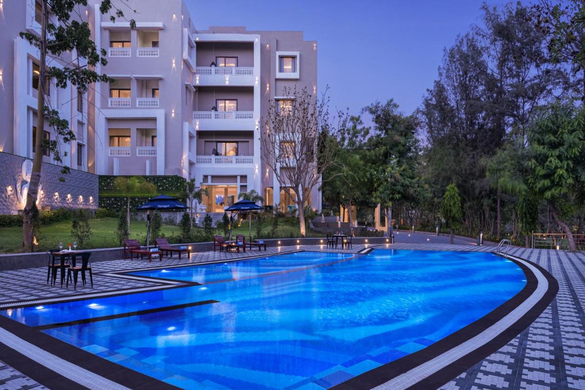 a swimming pool in front of a building at Essentia Luxury Resort & Spa Udaipur in Udaipur