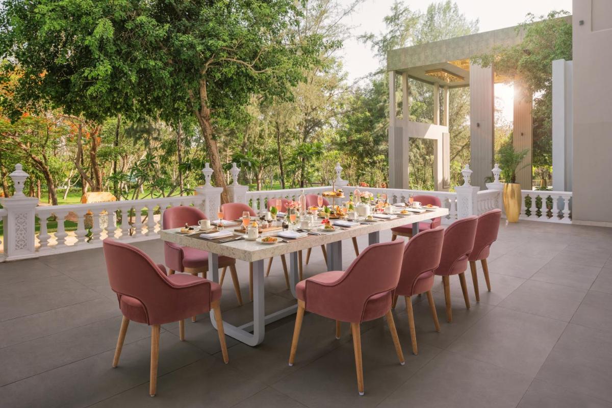 a long table with chairs and a table with food on it at Essentia Luxury Resort & Spa Udaipur in Udaipur