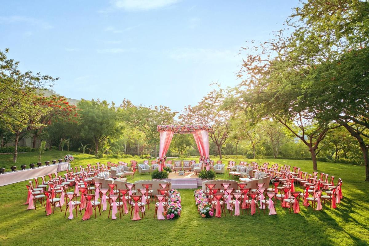 a garden wedding with a pink arch and chairs at Essentia Luxury Resort & Spa Udaipur in Udaipur