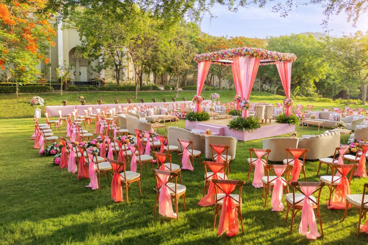 a long table with chairs and a table with an arch at Essentia Luxury Resort & Spa Udaipur in Udaipur