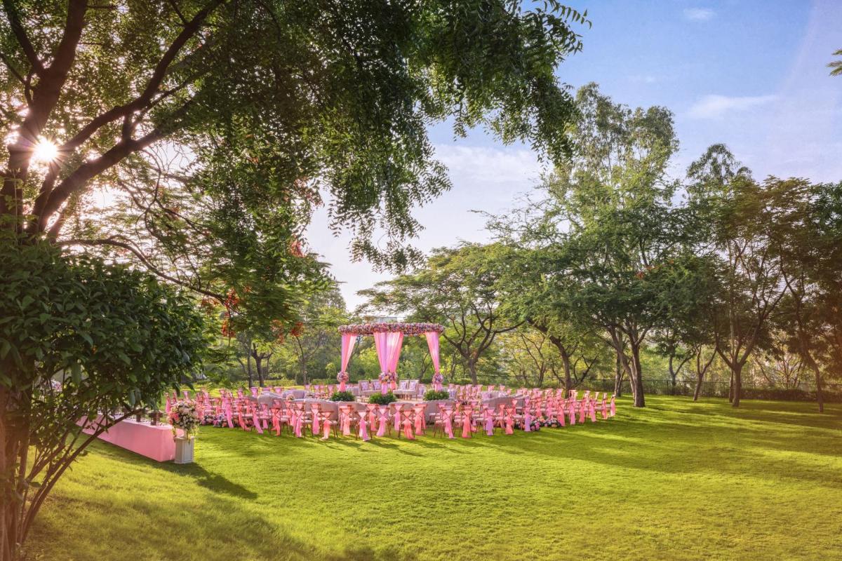 a row of tables with pink chairs in a park at Essentia Luxury Resort & Spa Udaipur in Udaipur