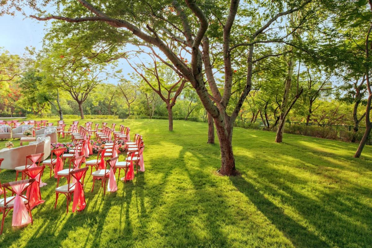 a row of tables and chairs in a field with trees at Essentia Luxury Resort & Spa Udaipur in Udaipur