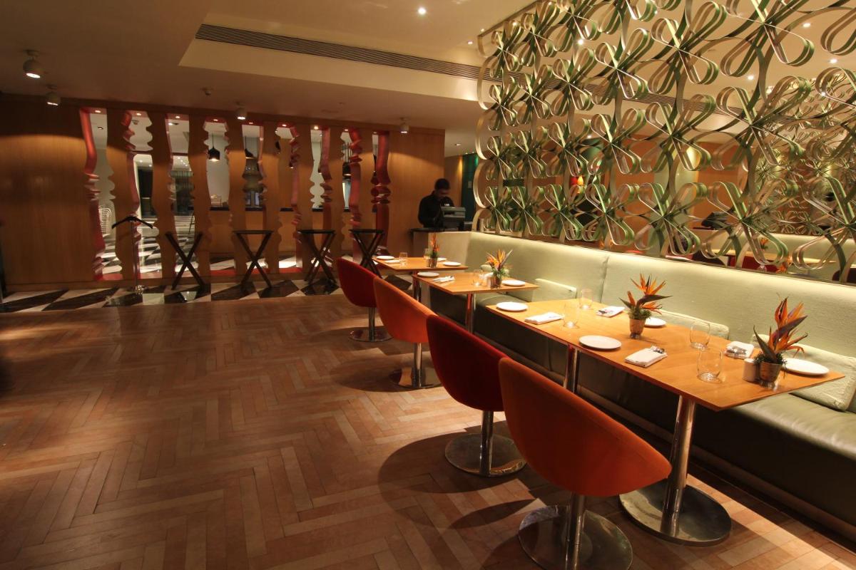 a restaurant with long tables and a green couch at The Park Hyderabad, Banjara Hills near Hussain Sagar Lake in Hyderabad a restaurant with long tables and a green couch at The Park Hyderabad, Banjara Hills near Hussain Sagar Lake in Hyderabad