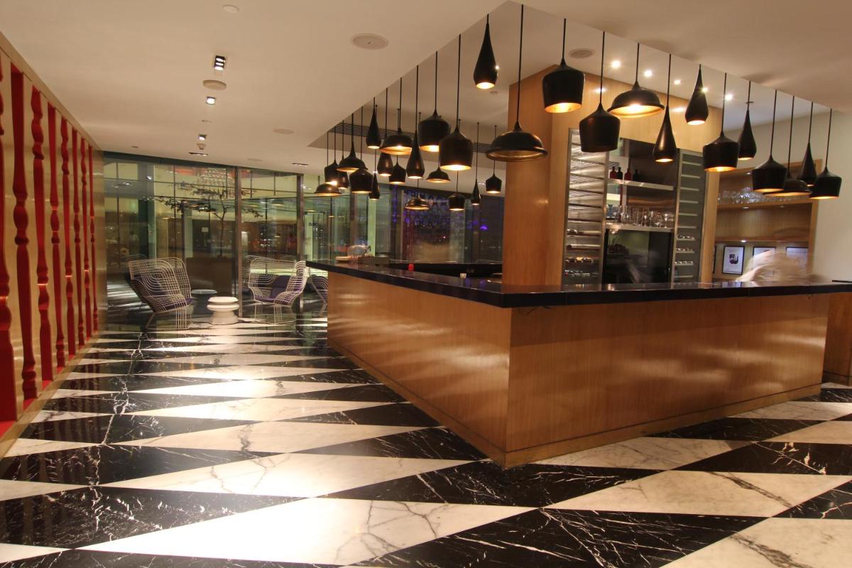 a bar in a restaurant with a black and white tile floor at The Park Hyderabad, Banjara Hills near Hussain Sagar Lake in Hyderabad a bar in a restaurant with a black and white tile floor at The Park Hyderabad, Banjara Hills near Hussain Sagar Lake in Hyderabad