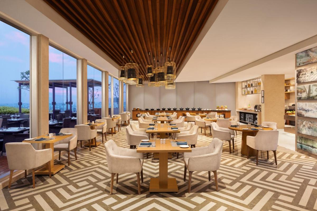 a dining room with tables and chairs and large windows at Marriott Executive Apartments Hyderabad in Hyderabad
