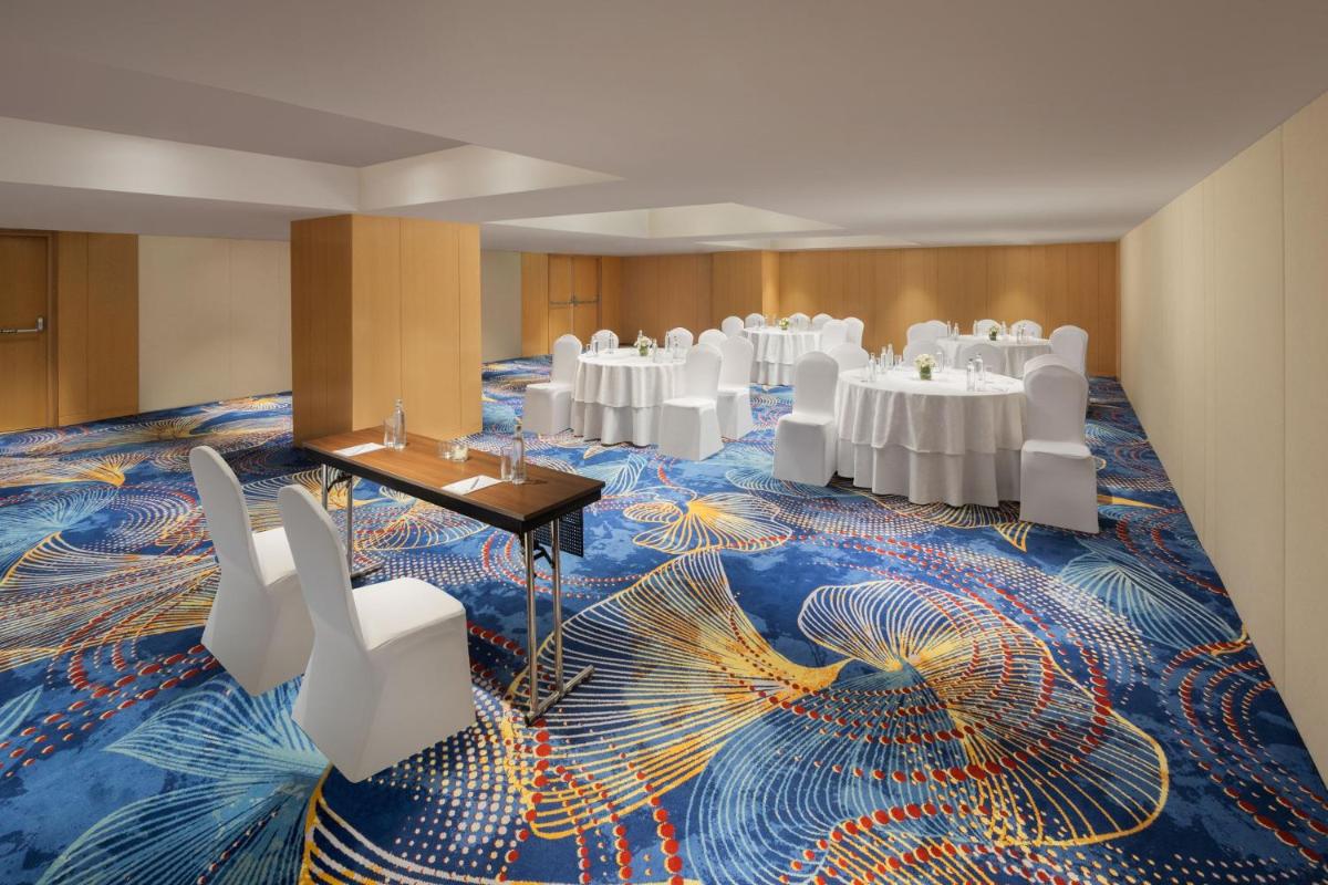 a conference room with white tables and chairs on a colorful carpet at Marriott Executive Apartments Hyderabad in Hyderabad