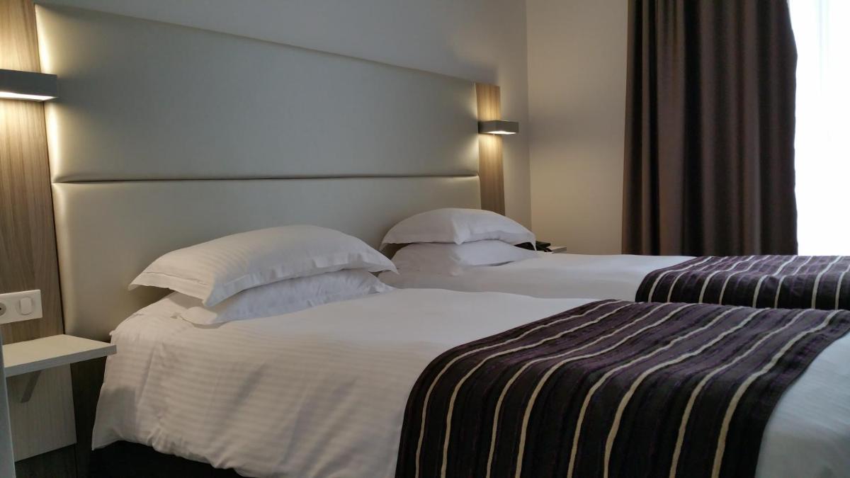 Un ou plusieurs lits dans un hébergement de l'établissement Brit Hotel de Grignan Vichy