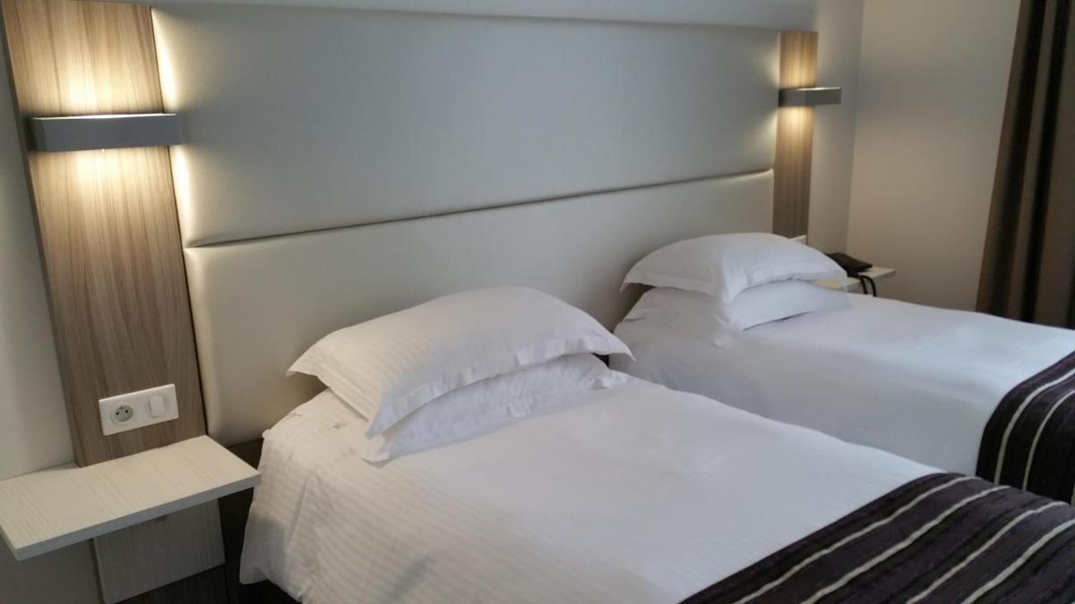 Un ou plusieurs lits dans un hébergement de l'établissement Brit Hotel de Grignan Vichy