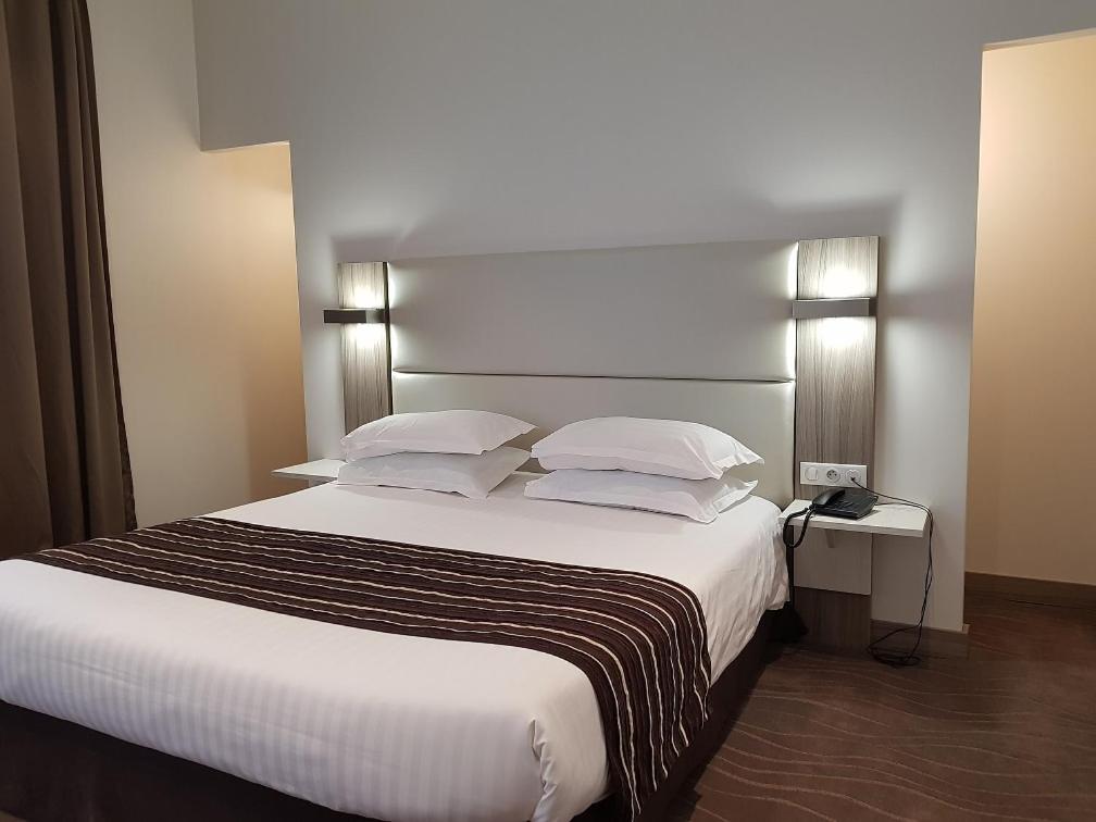 Un ou plusieurs lits dans un hébergement de l'établissement Brit Hotel de Grignan Vichy