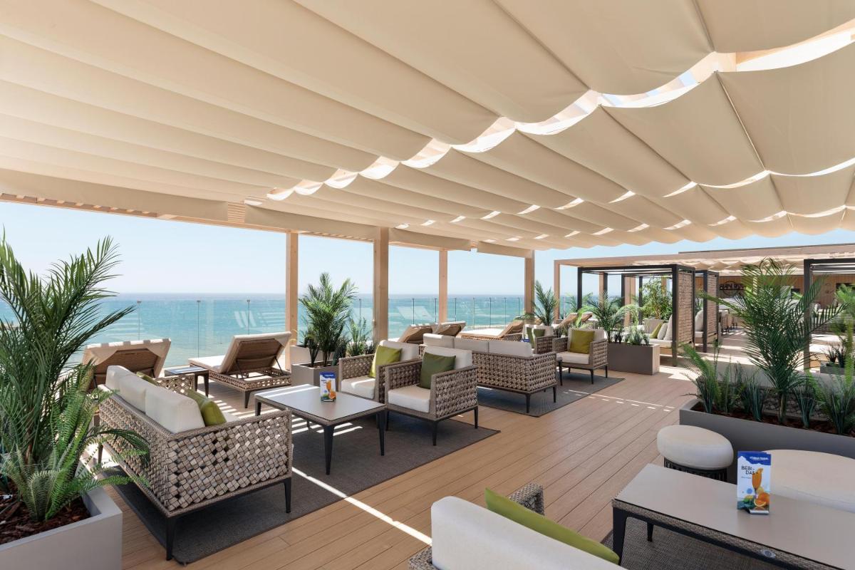 Un patio al aire libre con sillas y mesas y el océano. en Hotel Best Triton, en Benalmádena 155 fotos más
