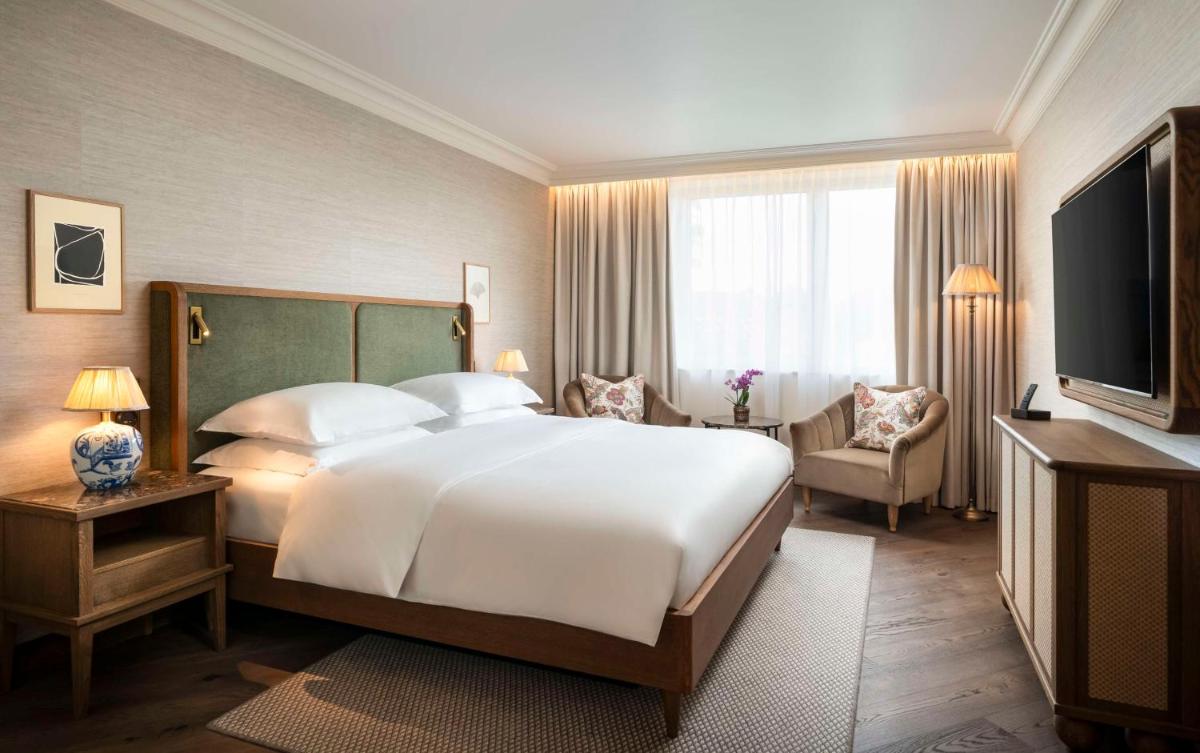 ein Schlafzimmer mit einem großen Bett und einem Fernseher in der Unterkunft Brunfels Hotel, in the Unbound Collection by Hyatt in Mainz + 64 Fotos