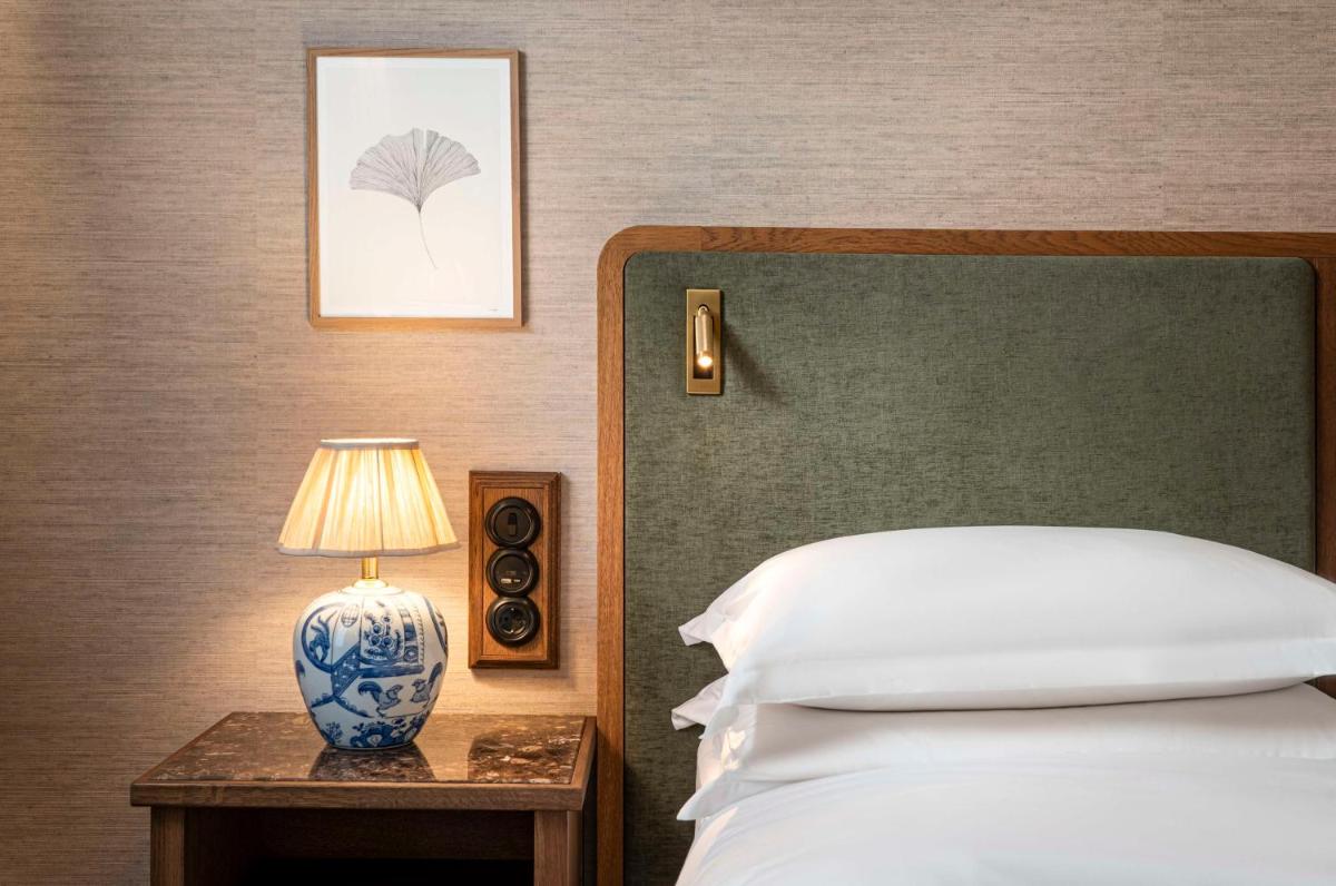 ein Schlafzimmer mit einem Bett und einem Tisch mit einer Lampe in der Unterkunft Brunfels Hotel, in the Unbound Collection by Hyatt in Mainz