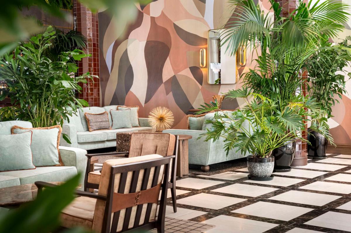 ein Wohnzimmer mit einem Sofa, Stühlen und Pflanzen in der Unterkunft Brunfels Hotel, in the Unbound Collection by Hyatt in Mainz