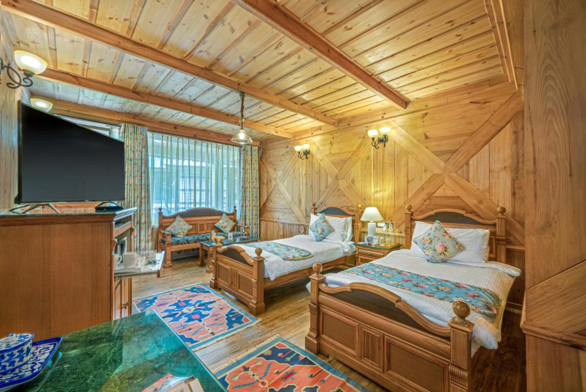 a bedroom with two beds and a flat screen tv at Storii By ITC Hotels Urvashis Retreat, Manali in Manāli a bedroom with two beds and a flat screen tv at Storii By ITC Hotels Urvashis Retreat, Manali in Manāli