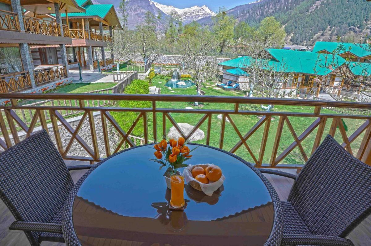a glass table with a vase of flowers on a balcony at Storii By ITC Hotels Urvashis Retreat, Manali in Manāli a glass table with a vase of flowers on a balcony at Storii By ITC Hotels Urvashis Retreat, Manali in Manāli