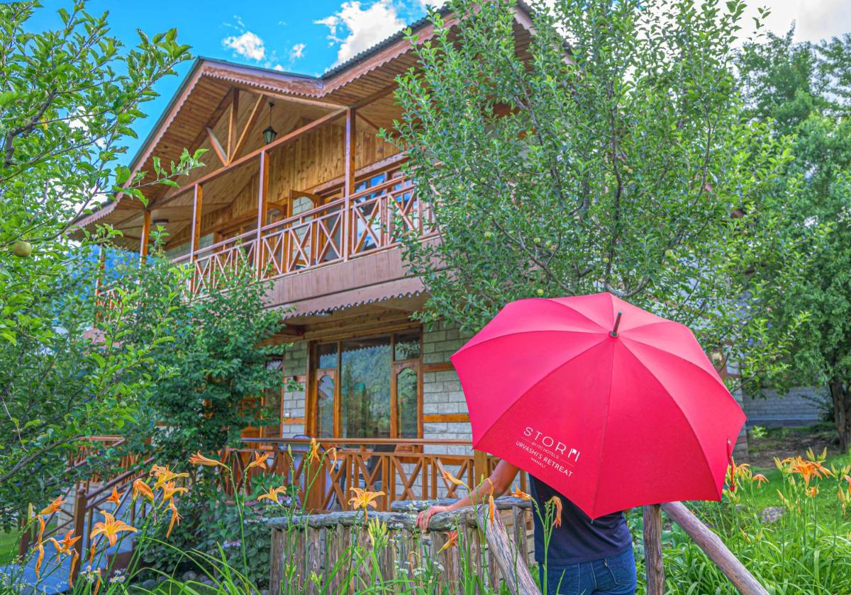 a person holding a red umbrella in front of a house at Storii By ITC Hotels Urvashis Retreat, Manali in Manāli a person holding a red umbrella in front of a house at Storii By ITC Hotels Urvashis Retreat, Manali in Manāli