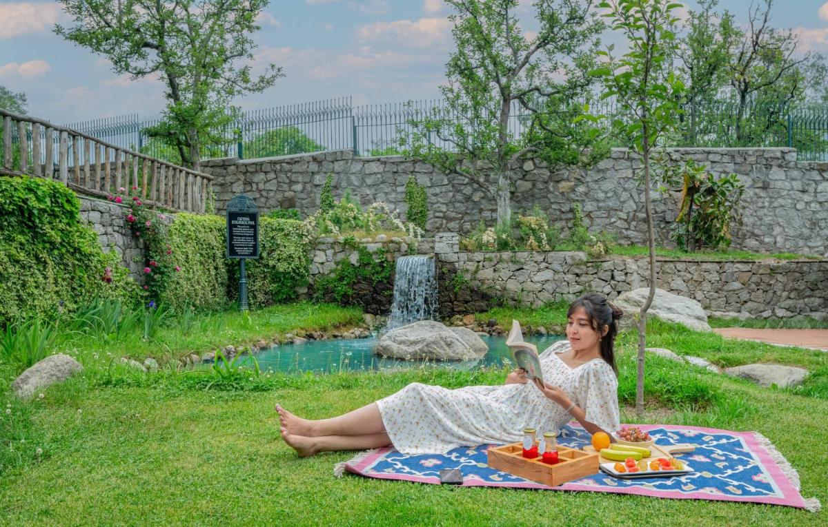 a woman sitting on a blanket in the grass at Storii By ITC Hotels Urvashis Retreat, Manali in Manāli a woman sitting on a blanket in the grass at Storii By ITC Hotels Urvashis Retreat, Manali in Manāli